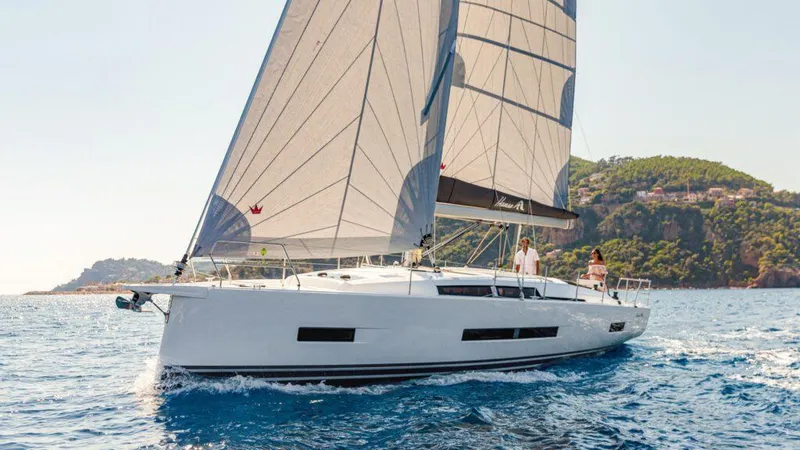 Slide: The Image of 2025 Hanse 410 yacht sailing on clear blue waters near a scenic coastline. - 12