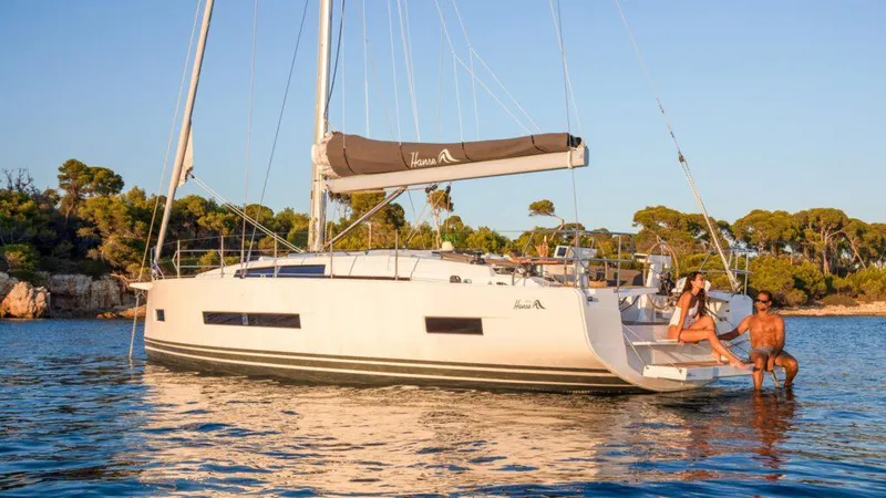 Slide: The Image of 2025 Hanse 410 sailboat anchored in serene waters with two people relaxing on deck. - 14