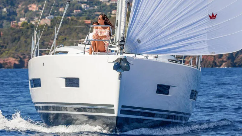 Slide: The Image of 2025 Hanse 410 sailboat cruising with a person on deck, scenic coastal background. - 6