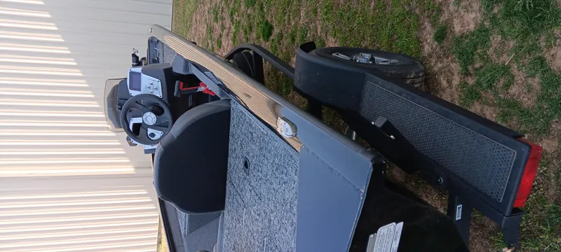 Slide: The Image of 2025 Tracker Pro Team 190 boat on trailer, side view, parked on grass. - 12