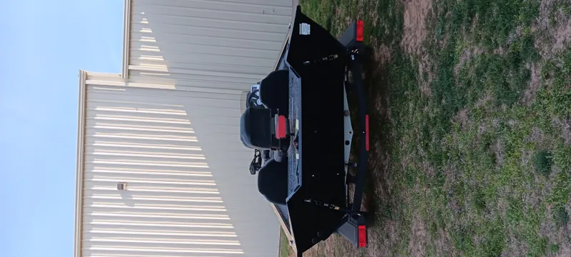 Slide: The Image of 2025 Tracker Pro Team 190 boat on trailer, parked beside a building. - 2