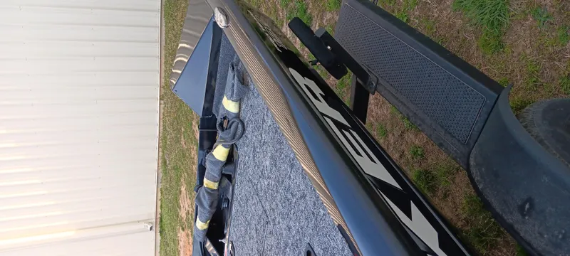 Slide: The Image of 2025 Tracker Pro Team 190 boat on trailer, side view, parked on grass. - 6