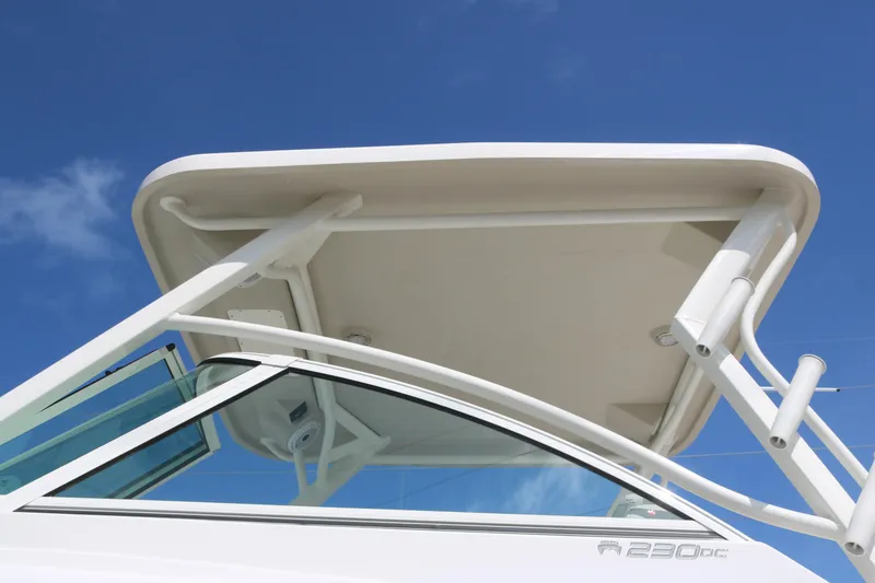 Slide: The Image of 2025 World Cat 230 DC boat with sleek design and sturdy canopy against blue sky. - 2