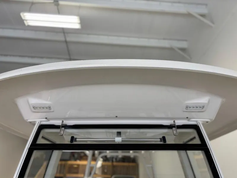 Slide: The Image of 2017 Robalo R302 Center Console boat's T-top and windshield in a showroom. - 22