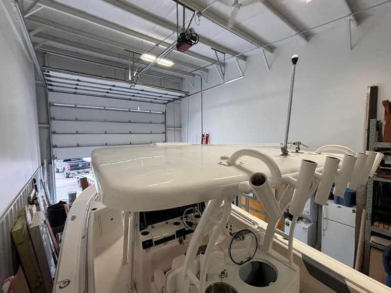 Slide: The Image of 2017 Robalo R302 Center Console boat in a garage, showcasing its helm and T-top. - 35
