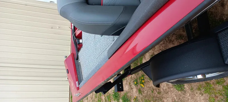 Slide: The Image of 2022 Tracker Pro Team 175 TXW boat, red exterior, gray seating, parked on grass. - 4