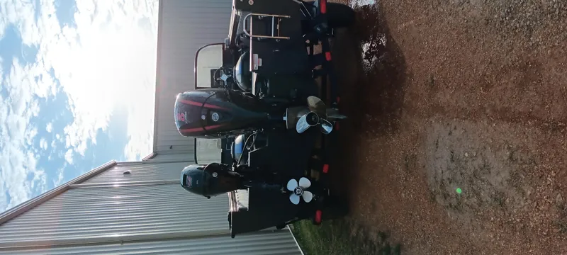 Slide: The Image of 2025 Ranger VX1788 WT boat with dual motors parked on gravel near a metal building. - 2