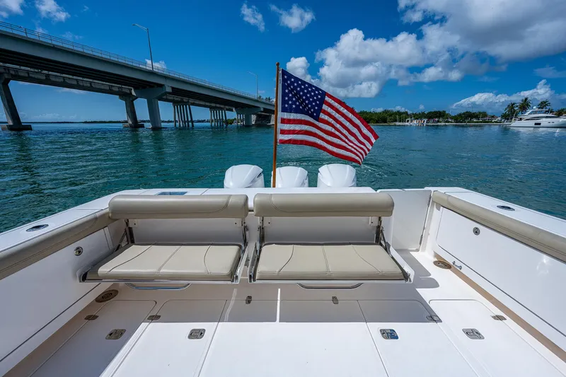 Slide: The Image of 2018 Pursuit OS 385 Offshore boat with American flag, near a bridge on a sunny day. - 11