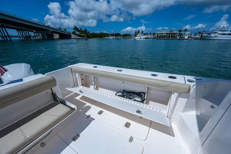 Slide: The Image of 2018 Pursuit OS 385 Offshore boat deck with seating, near a bridge and marina. - 13
