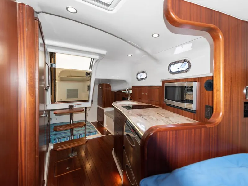Slide: The Image of 2018 Pursuit OS 385 Offshore yacht interior with wood finish, kitchenette, and seating area. - 27