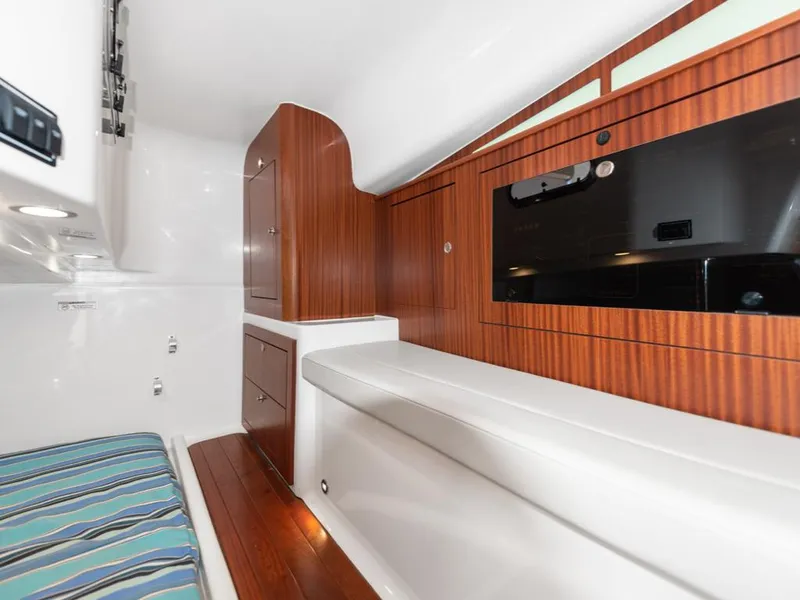 Slide: The Image of 2018 Pursuit OS 385 Offshore cabin interior with wood paneling and striped seating. - 33