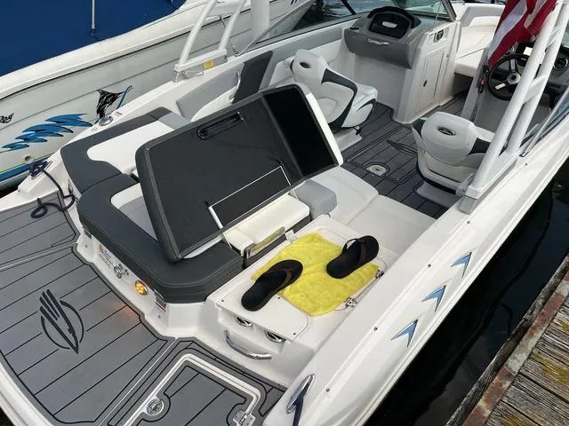 Slide: The Image of 2022 Chaparral 21 SSi boat interior with seating, storage, and flip-flops on deck. - 4