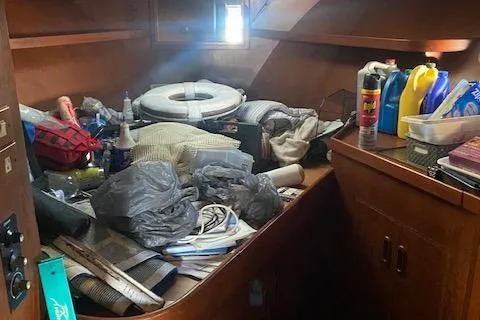 Slide: The Image of Cluttered cabin interior of a 1987 President 36 boat with various supplies and cleaning products. - 11