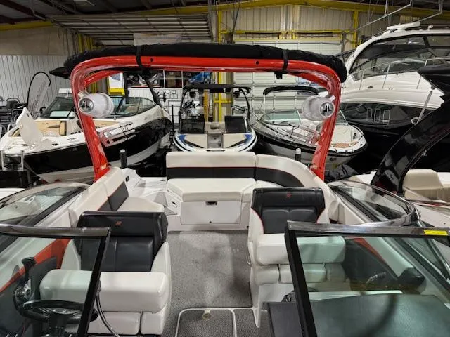 Slide: The Image of 2016 Four Winns TS242 boat interior with red accents, docked among other boats in a showroom. - 6