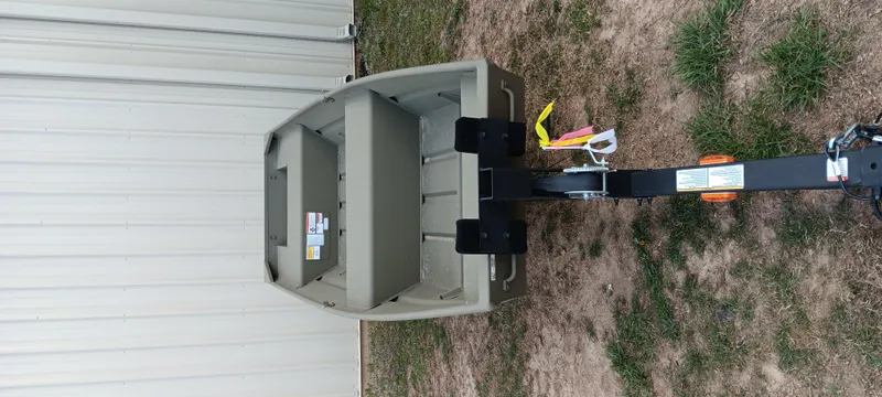 Slide: The Image of 2025 Tracker Grizzly 1436 Utility boat on trailer, parked beside a building. - 6