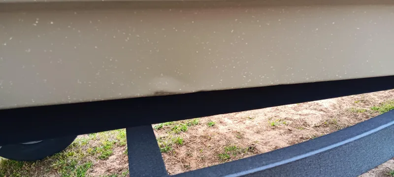 Slide: The Image of 2025 Tracker Grizzly 1436 Utility boat with minor hull dent, parked on grass. - 7