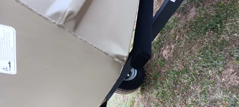 Slide: The Image of 2025 Tracker Grizzly 1436 Utility trailer on grass, close-up view of wheel and frame. - 8