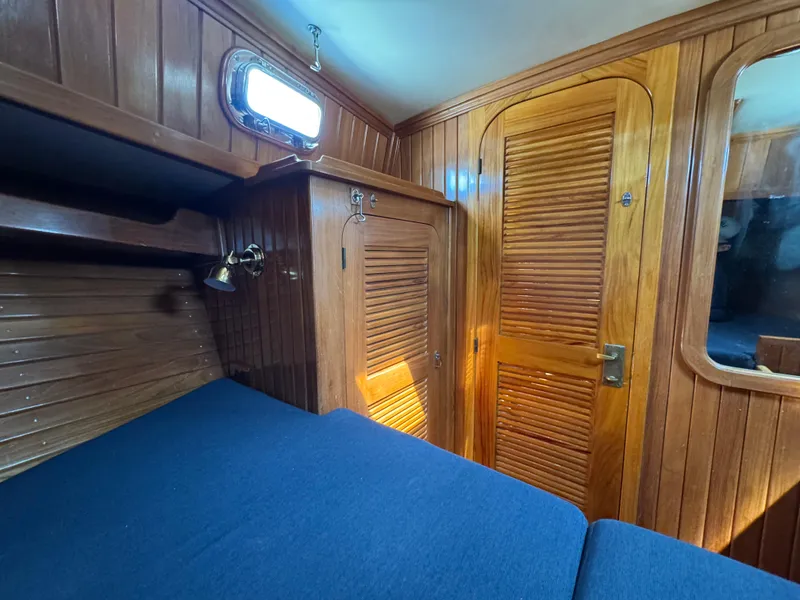 Slide: The Image of Interior of 1988 Cabo Rico 38XL sailboat with wooden paneling and blue upholstery. - 14
