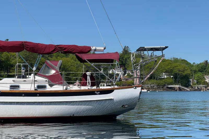 Slide: The Image of 1988 Cabo Rico 38XL sailboat with maroon canopy, anchored on calm water. - 4