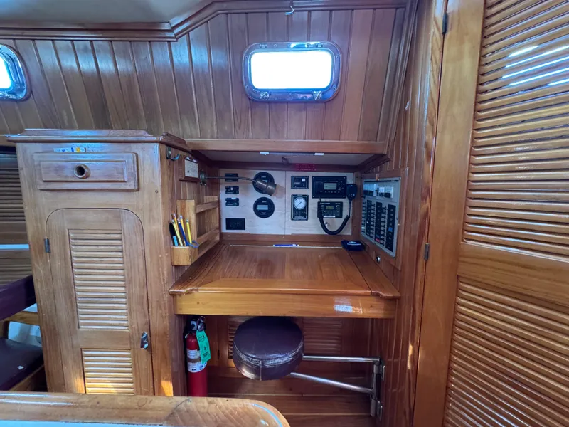 Slide: The Image of Cabo Rico 38XL 1988 yacht interior with navigation station, wooden paneling, and control instruments. - 42