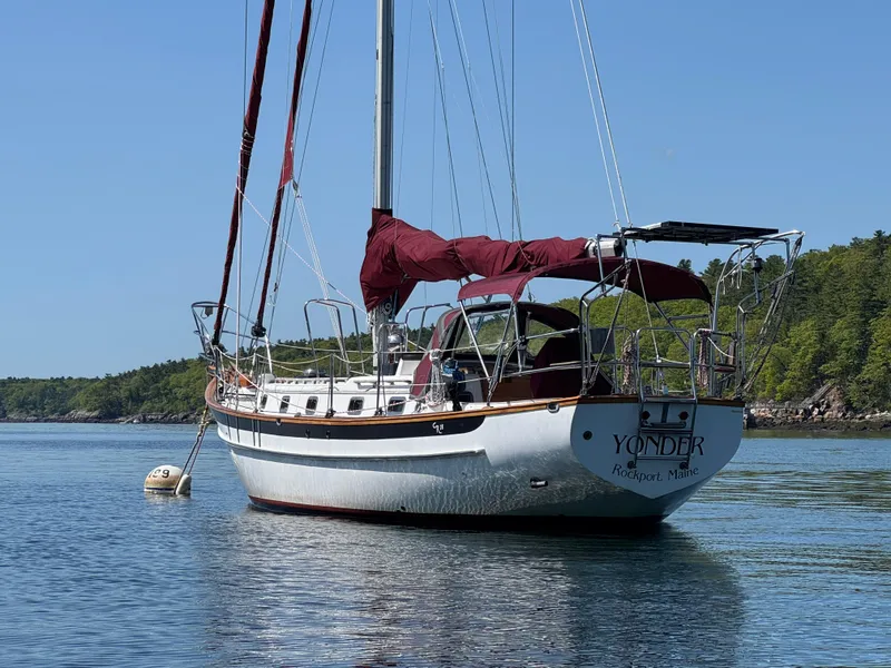 Slide: The Image of Sailboat Cabo Rico 38XL, 1988 model, anchored in calm waters with lush green shoreline. - 5