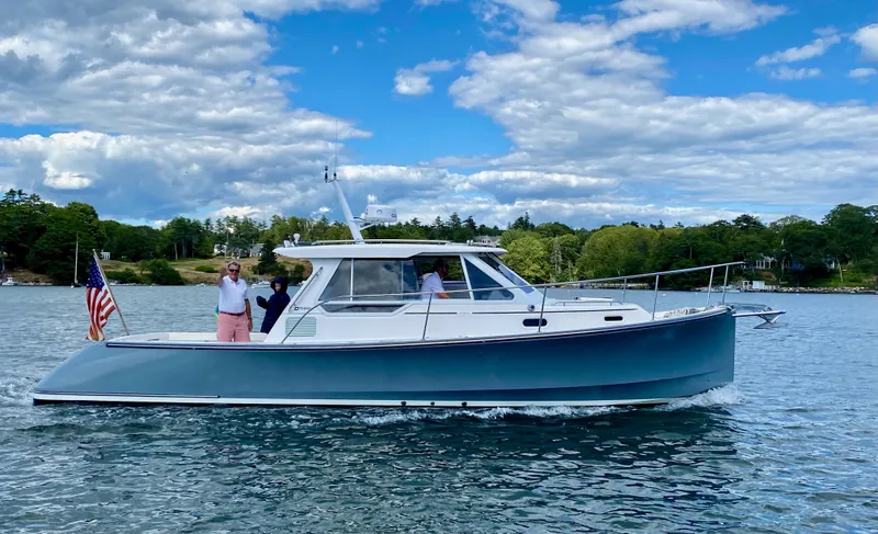 The Image of 2005 True North 33 boat cruising on a scenic lake under a partly cloudy sky. - 0
