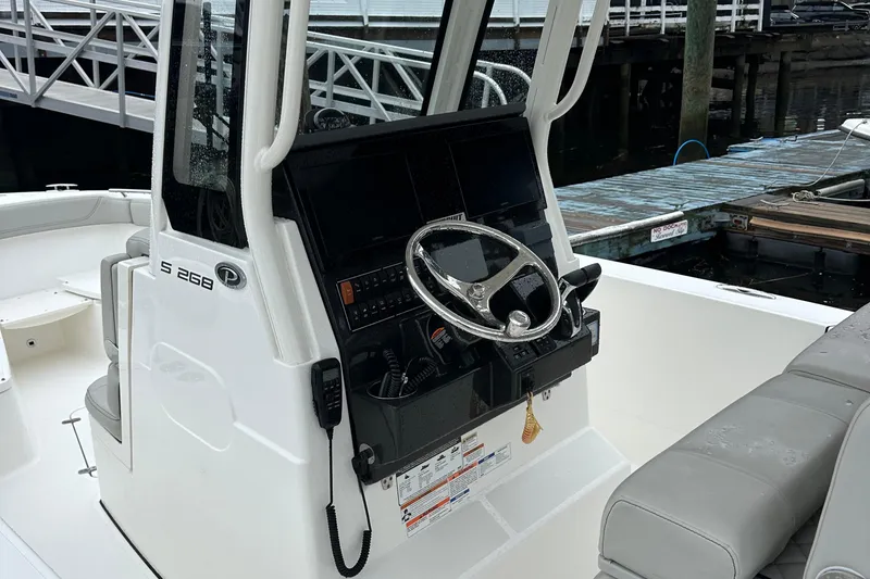 Slide: The Image of 2022 Pursuit S 268 boat console with steering wheel and controls at dock. - 6