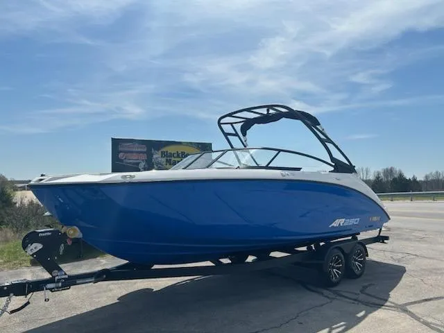 Slide: The Image of 2025 Yamaha Boats AR250 in blue on trailer under clear sky. - 1
