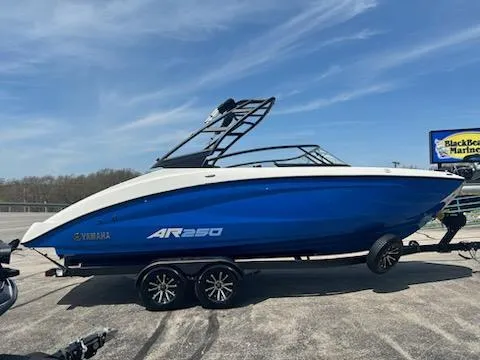 Slide: The Image of 2025 Yamaha AR250 boat in blue on a trailer, parked outdoors under a clear sky. - 4