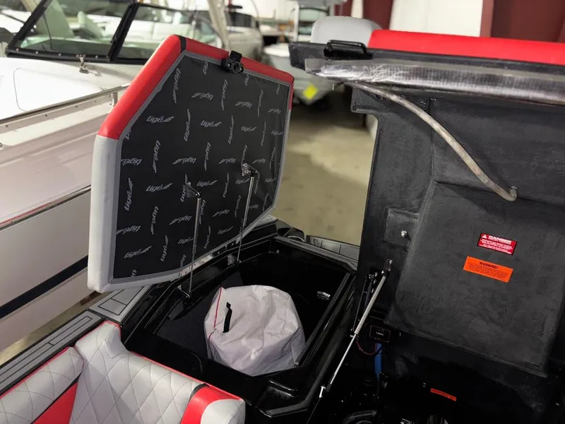 Slide: The Image of 2018 Tigé RZX3 boat storage compartment with open hatch, featuring red and white interior. - 19