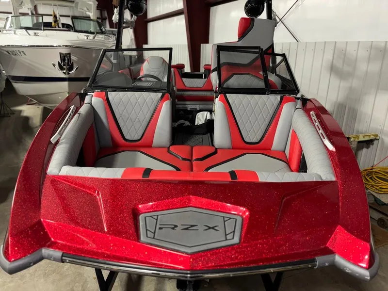 Slide: The Image of 2018 Tigé RZX3 boat, red and gray interior, parked indoors. - 2