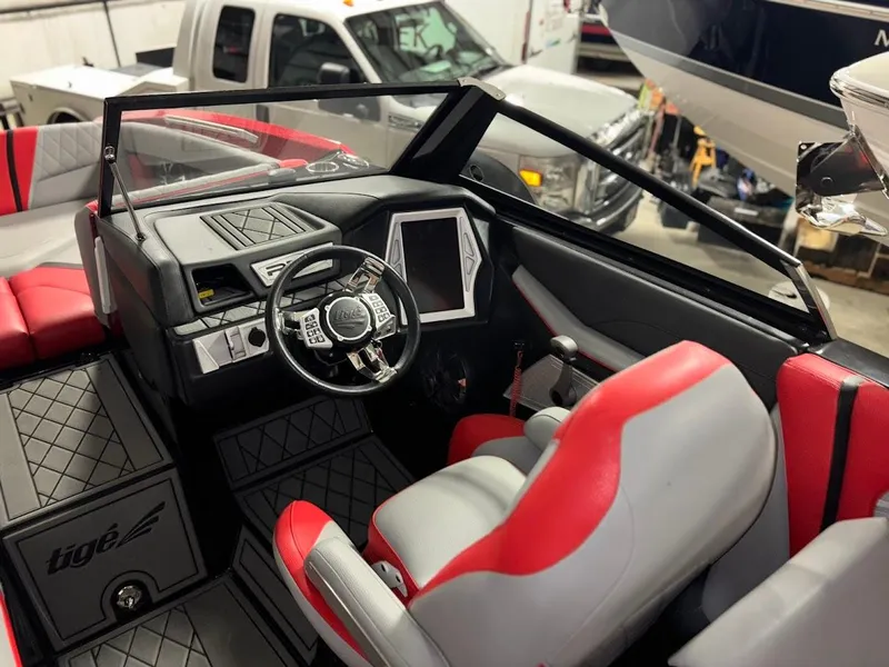 Slide: The Image of 2018 Tigé RZX3 boat interior with red and gray seating, steering wheel, and dashboard. - 20