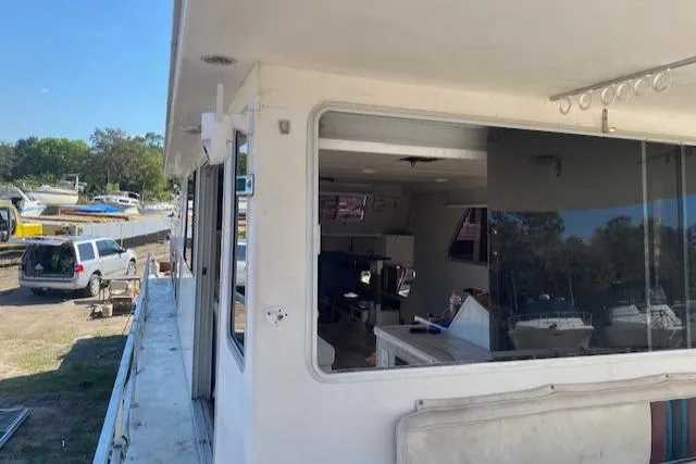 Slide: The Image of 1989 Gibson 50 Classic houseboat with large windows and visible interior, docked outdoors. - 11