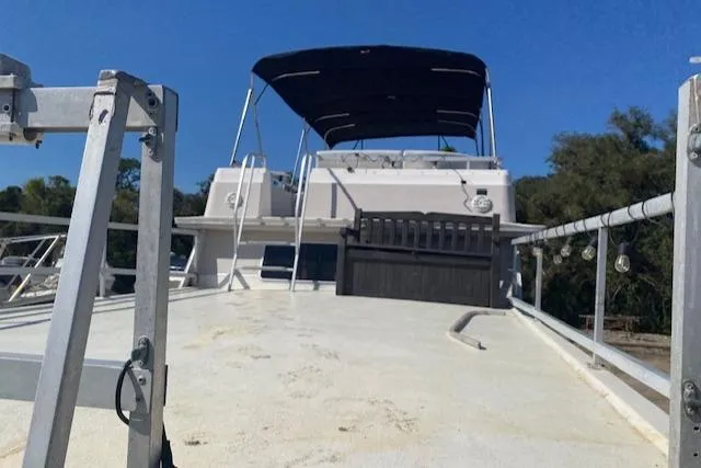Slide: The Image of 1989 Gibson 50 Classic boat deck with canopy and ladder, under clear blue sky. - 2
