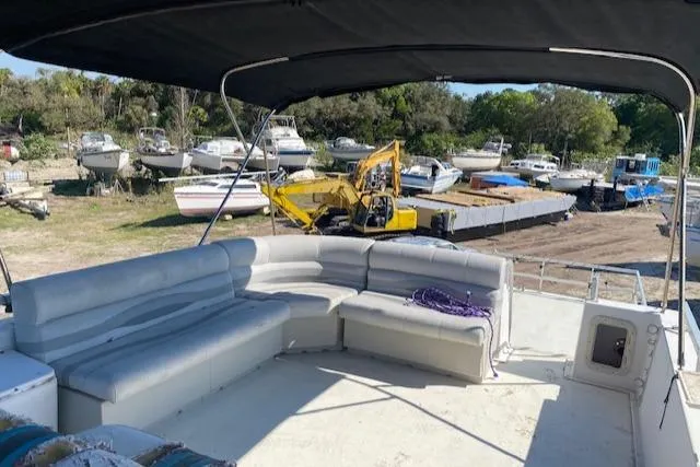 Slide: The Image of 1989 Gibson 50 Classic boat with spacious seating, docked near other boats and construction equipment. - 4