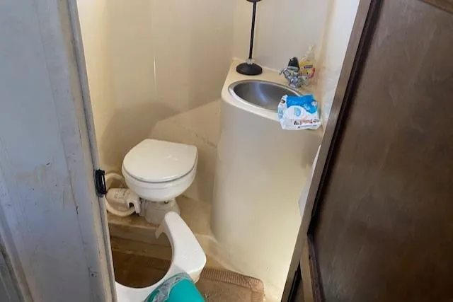 Slide: The Image of Small bathroom with toilet, corner sink, and toiletries on the counter. - 8