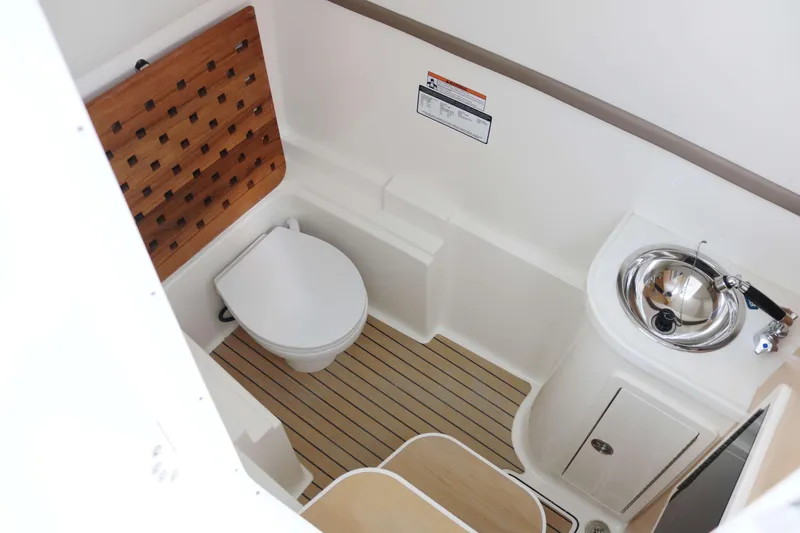 Slide: The Image of 2026 World Cat 325 DC boat bathroom with toilet, sink, and wooden accents. - 11
