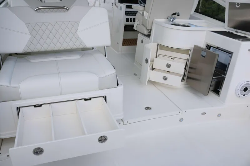 Slide: The Image of 2026 World Cat 325 DC boat interior with white seating, storage drawers, and a mini fridge. - 19