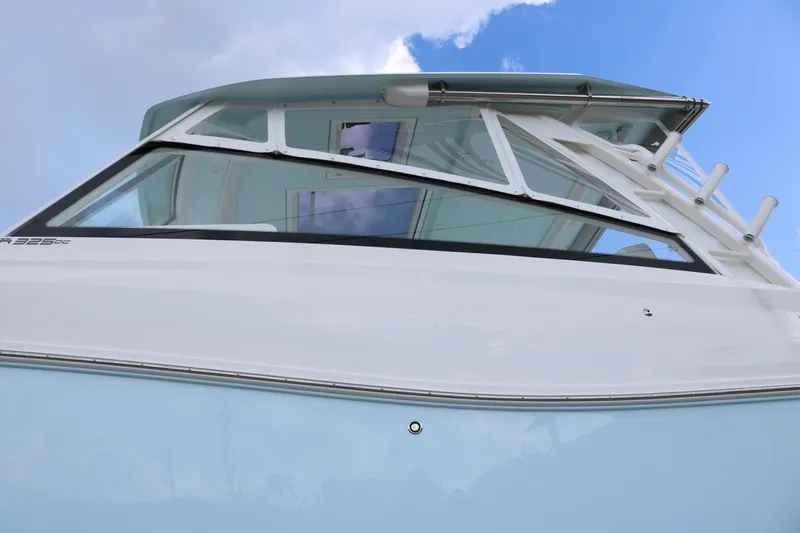 Slide: The Image of 2026 World Cat 325 DC boat, sleek design, white and blue exterior, under a clear sky. - 5