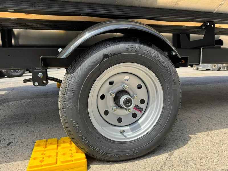 Slide: The Image of Trailer wheel of 2025 South Bay 18CR SE S Cruise, secured with yellow chock. - 21