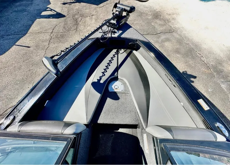 Slide: The Image of 2025 Lund 1875 Crossover XS boat interior with trolling motor, gray seating, and storage compartments. - 8