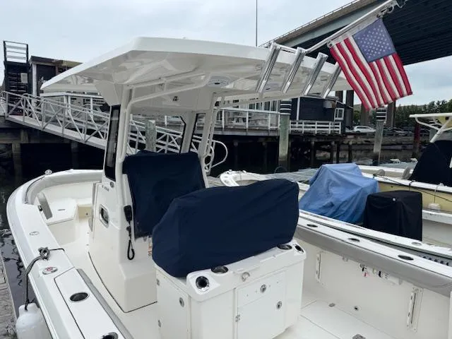 Slide: The Image of 2024 Pursuit S 268 boat docked, featuring covered seating and an American flag. - 19