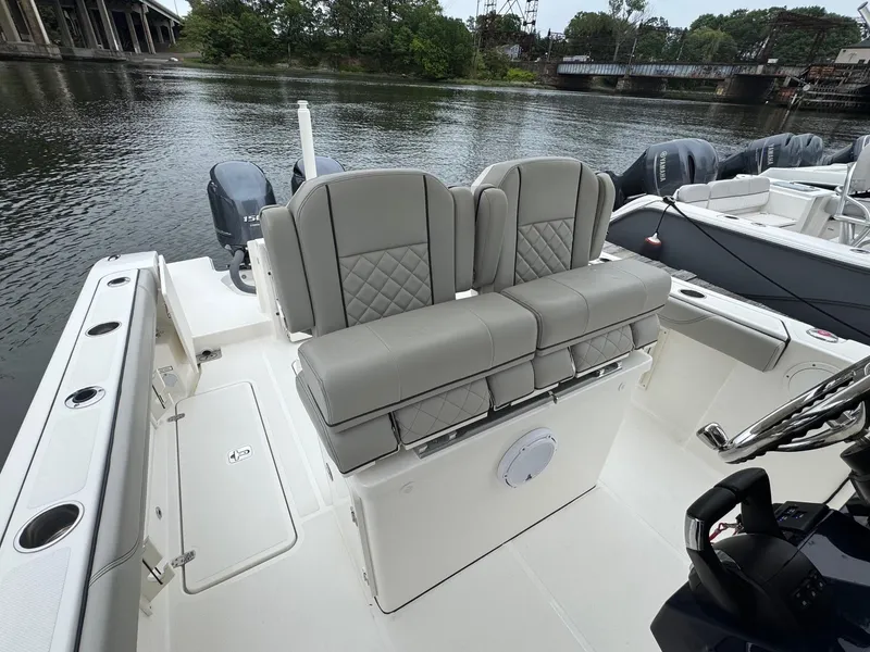 Slide: The Image of 2024 Pursuit S 268 boat with cushioned seating, docked by a scenic river. - 30