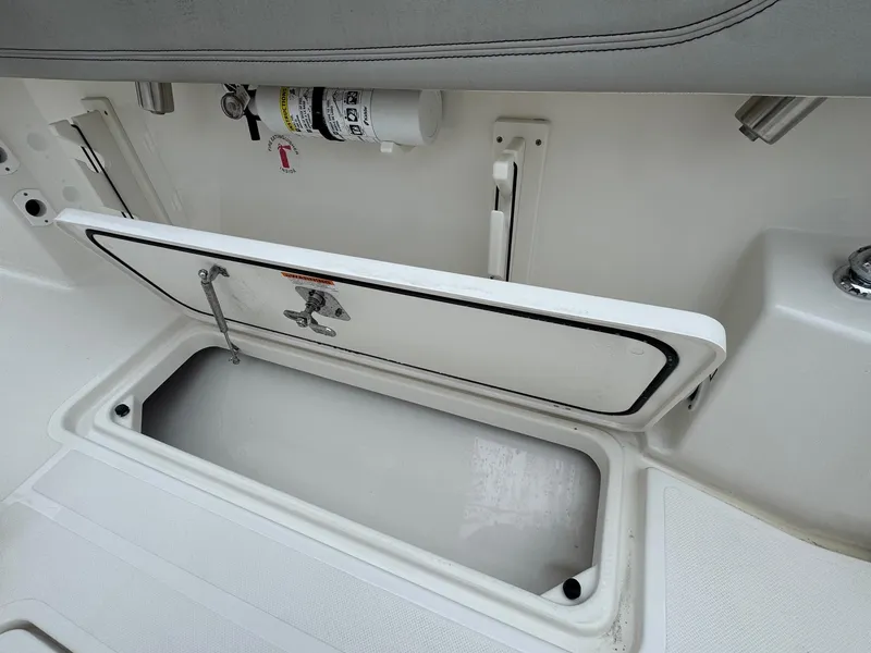 Slide: The Image of 2024 Pursuit S 268 boat storage compartment with open hatch and safety equipment. - 38