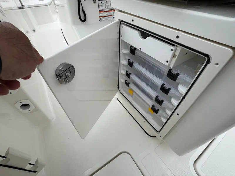 Slide: The Image of 2024 Pursuit S 268 boat storage compartment with organized tackle boxes. - 39