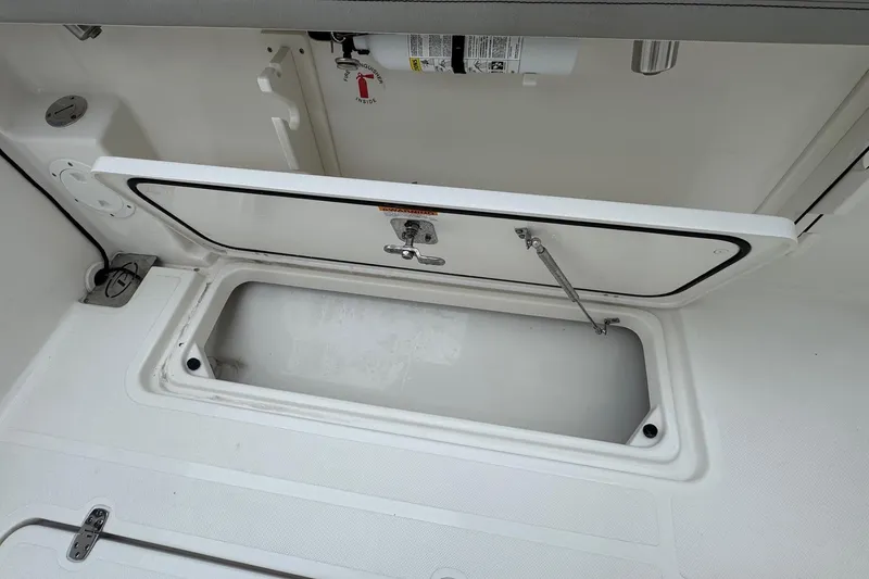 Slide: The Image of 2024 Pursuit S 268 boat storage compartment with open hatch and fire extinguisher. - 41