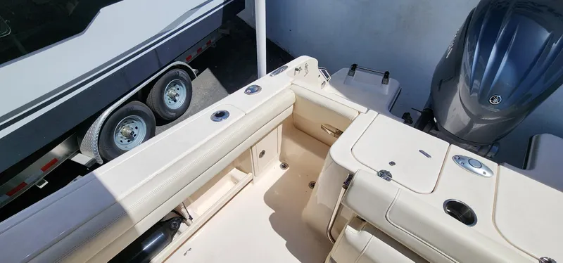 Slide: The Image of 2023 Grady-White Freedom 235 boat interior with seating and motor, parked beside a trailer. - 20