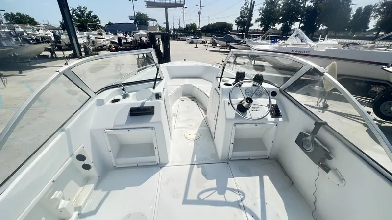 Slide: The Image of 1998 Pro Sports Walk Through boat named "Anonymous" on a trailer, parked outside a building. - 6