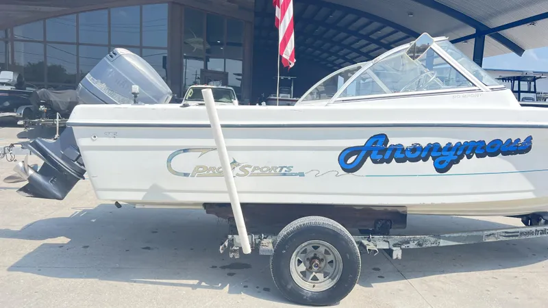 Slide: The Image of 1998 Pro Sports Walk Through boat on trailer, parked outside a building with an American flag. - 7