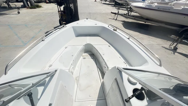 Slide: The Image of 1998 Pro Sports Walk Through boat with open deck and windshield, parked on concrete. - 9